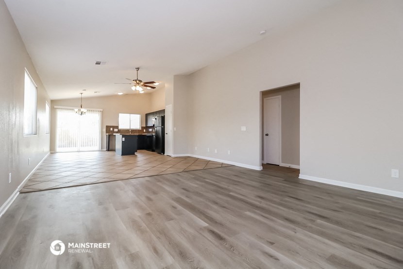 an empty living room with wood floors and a kitchen