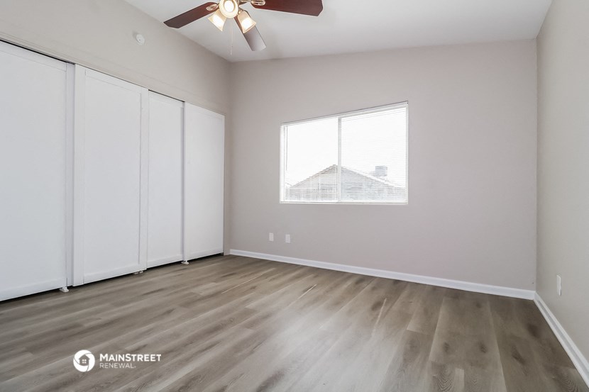 the living room of an empty house with a window and a ceiling fan