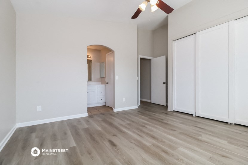 an empty living room with white walls and a ceiling fan