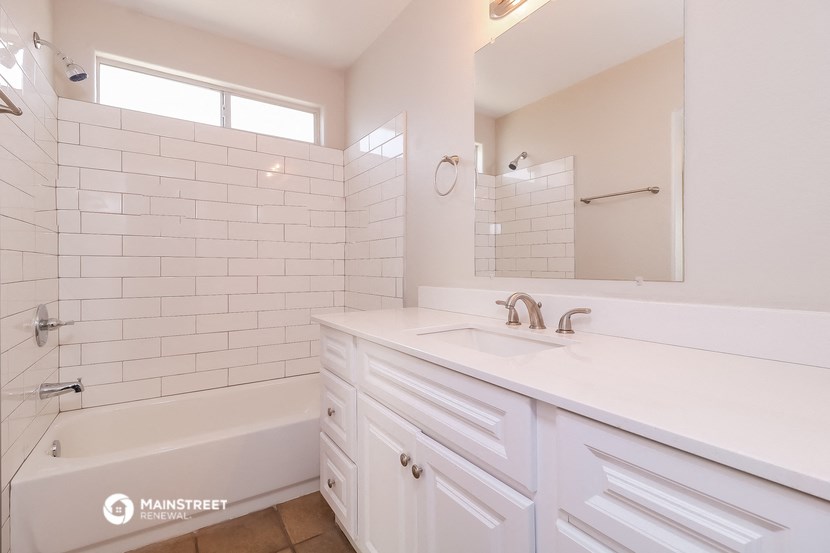 a bathroom with white cabinets and a tub and a sink and a mirror