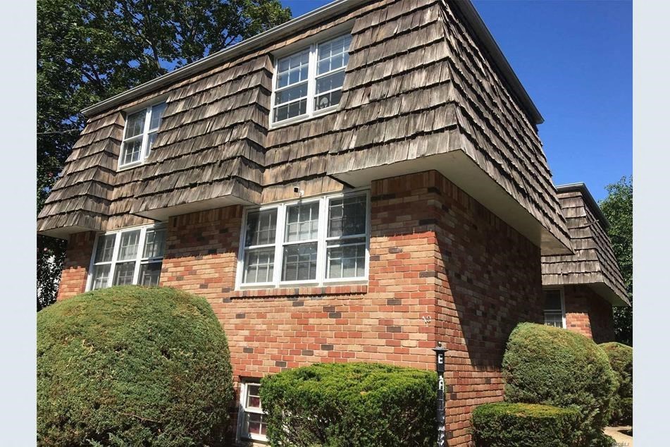 A house with a red brick wall and a shingled roof.
