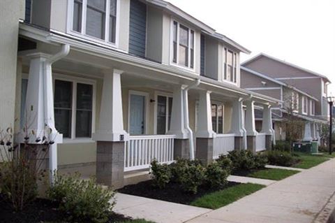 a row of houses with white pillars and a sidewalk