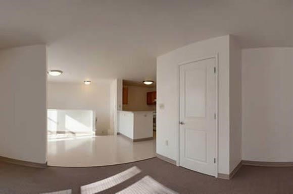 an empty living room and kitchen with a white door