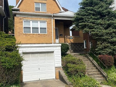 A house with a white garage door and a brick facade.