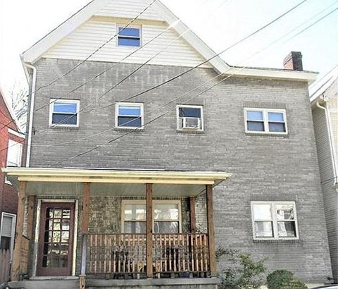 a gray brick house with a porch