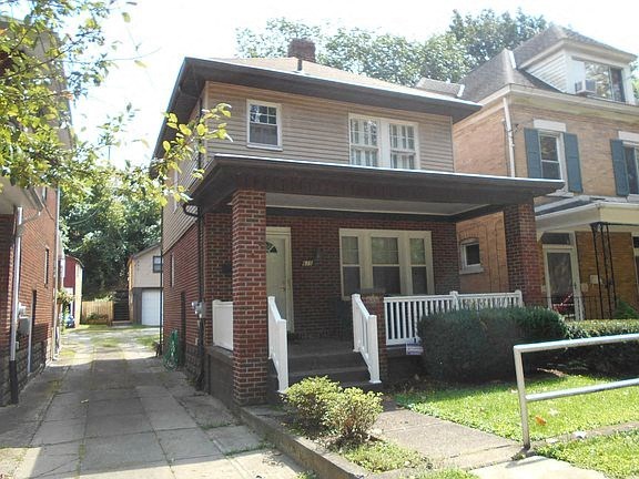 A house with a red brick facade and a white fence.