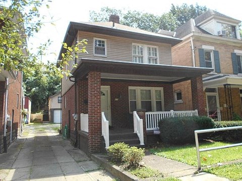 A house with a red brick facade and a white fence.