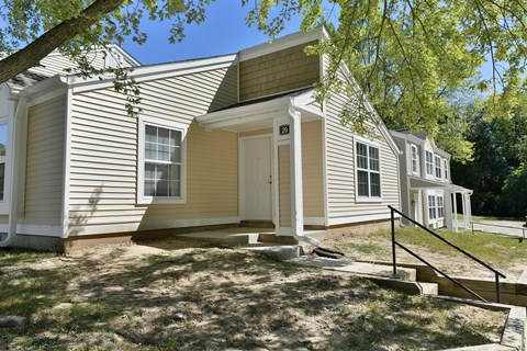 the front of a white house with a porch and stairs