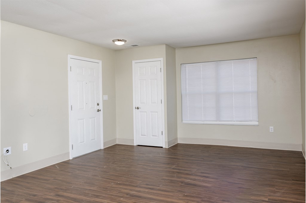 an empty living room with two doors and a window