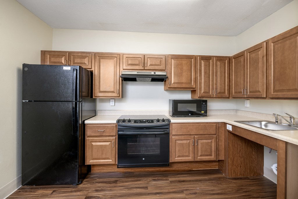 an empty kitchen with black appliances and wooden cabinets