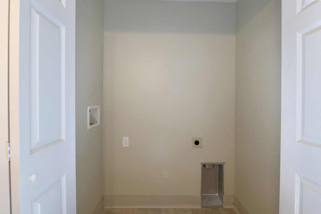 a room with a white wall and a silver trash can