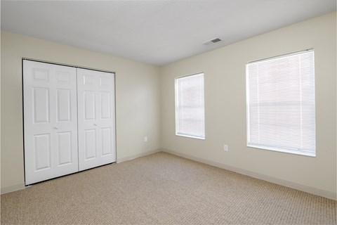 an empty room with a white door and two windows