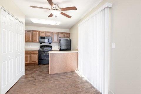 an empty kitchen with wood flooring and a ceiling fan