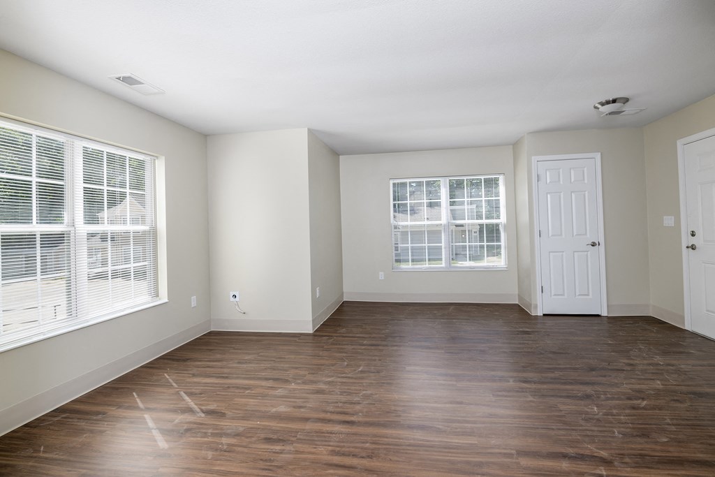 an empty living room with wood floors and a white door