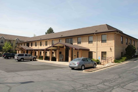 A parking lot in front of a building with cars parked.