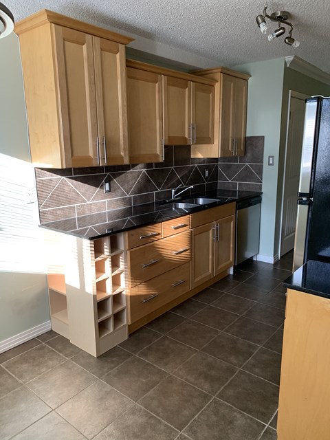 a kitchen with wooden cabinets and a black counter top