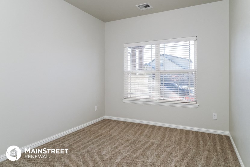 the bedroom of a small rental house with a large window