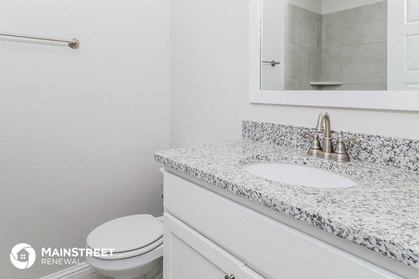 a bathroom with marble counter top and a toilet and sink