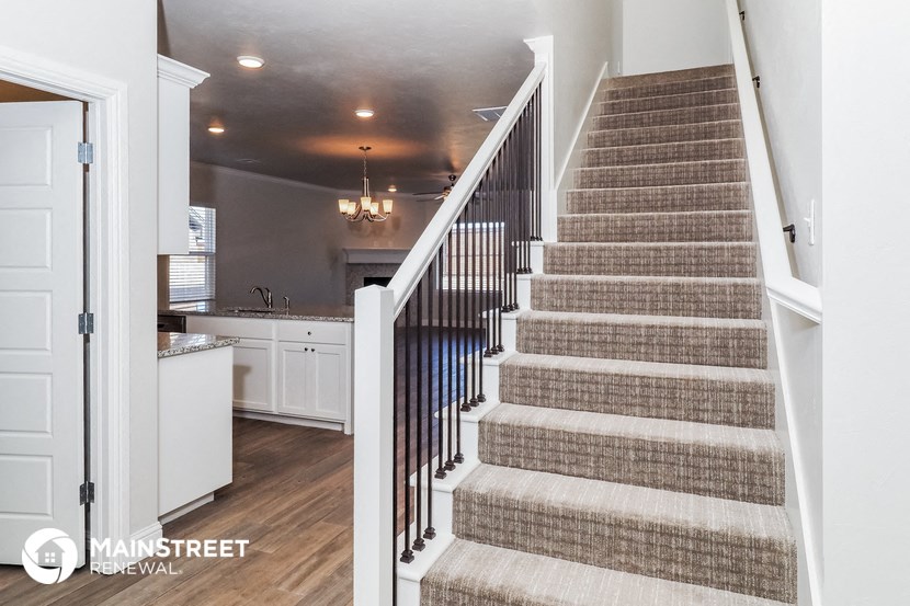 a staircase in a home with carpeted stairs and a kitchen