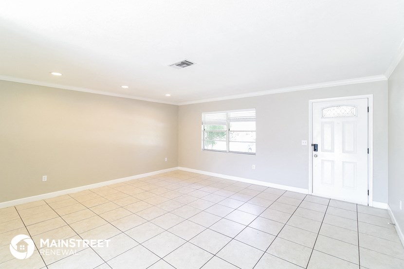 an empty living room with a white tile floor and a white door