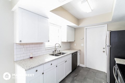 a white kitchen with white cabinets and a black refrigerator