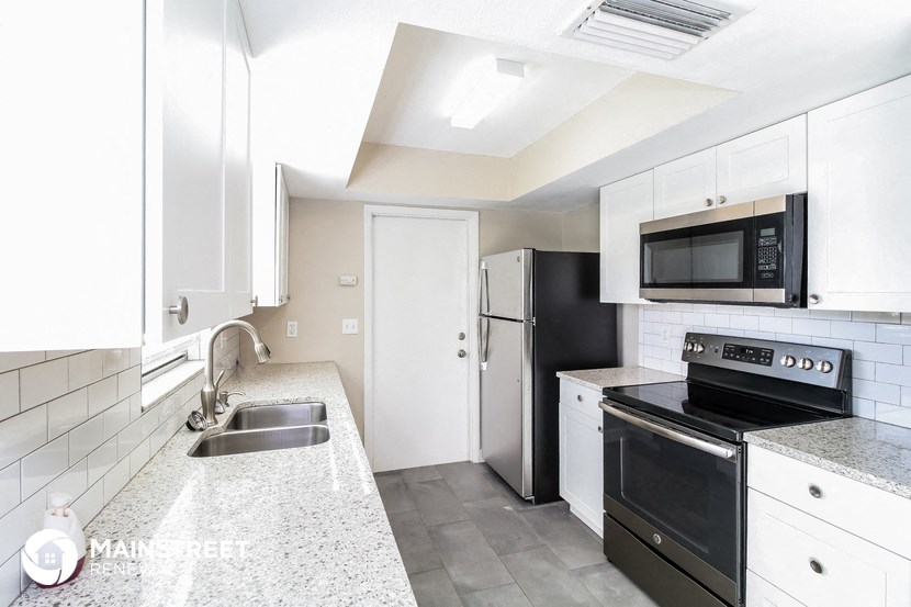 a kitchen with white cabinets and black appliances and a sink