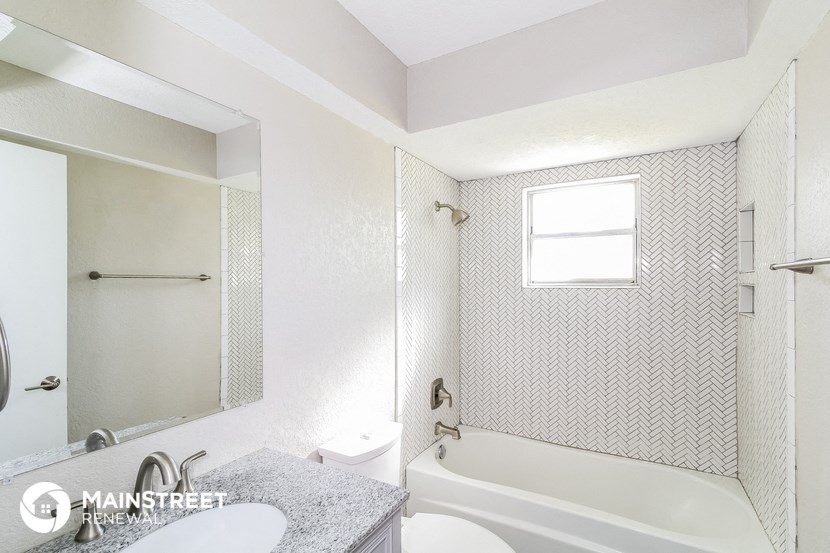 a white bathroom with a tub and a sink and a mirror
