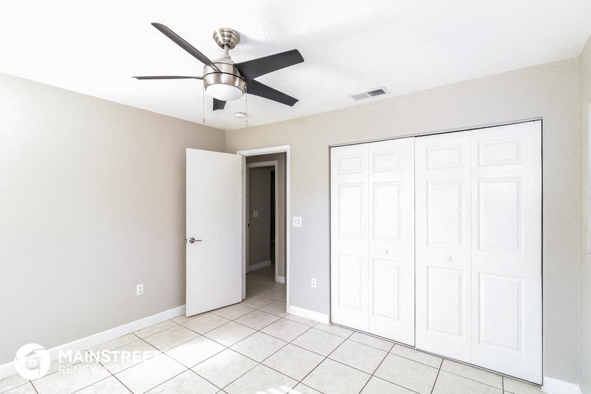 an empty room with a ceiling fan and a closet