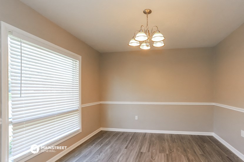 an empty dining room with a large window and wood flooring