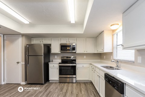 a renovated kitchen with white cabinets and stainless steel appliances
