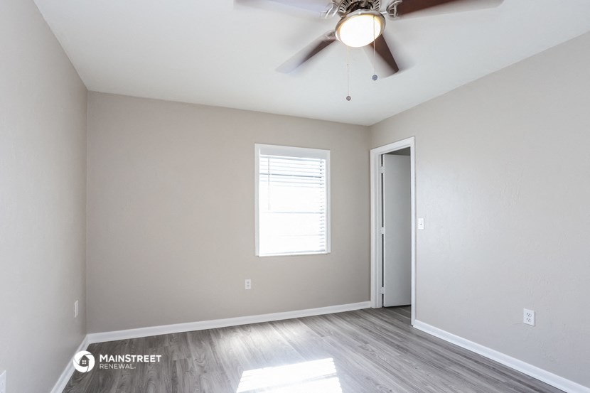 an empty room with a ceiling fan and a door