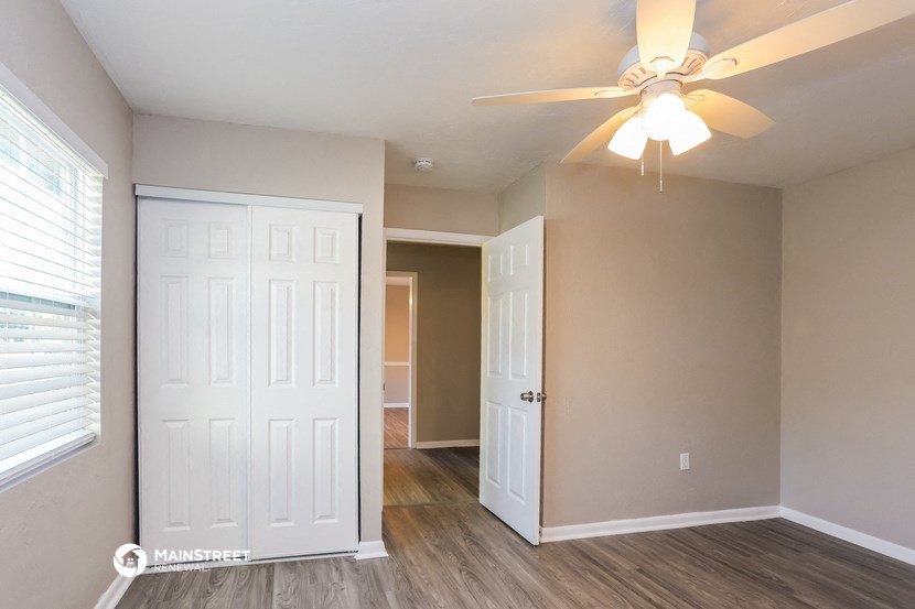 the living room of an empty home with a ceiling fan
