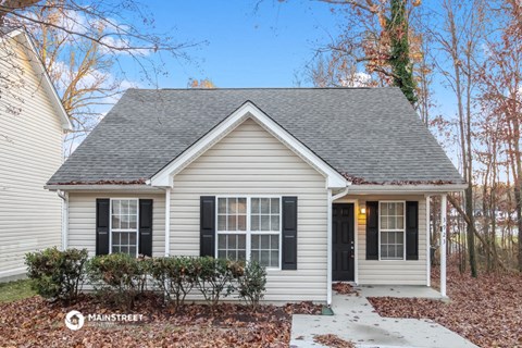 the front exterior of a small white house with black shutters
