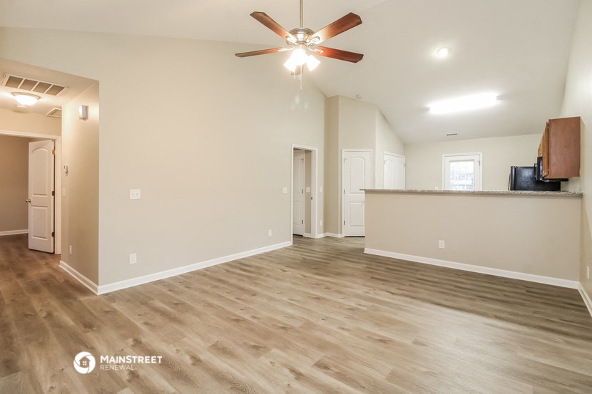 the living room and kitchen of an empty house with a ceiling fan