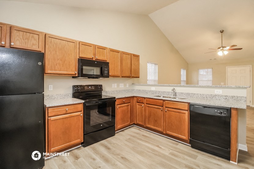 an empty kitchen with wooden cabinets and black appliances