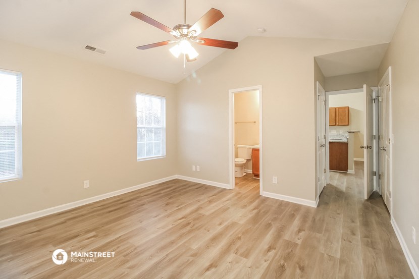 the spacious living room with hardwood flooring and a ceiling fan