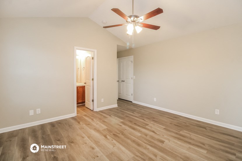 the spacious living room with wood flooring and a ceiling fan
