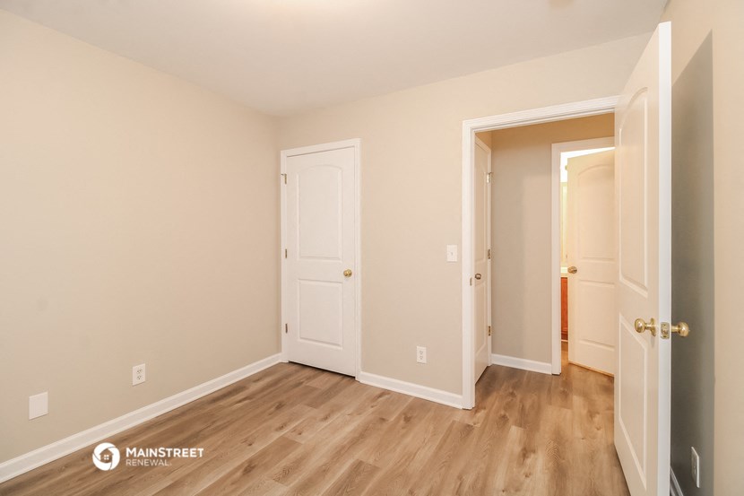 a bedroom with wood flooring and a door to a hallway