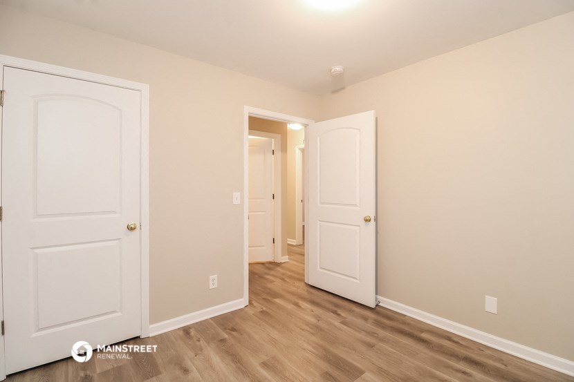 a bedroom with two doors and a hallway to two closets