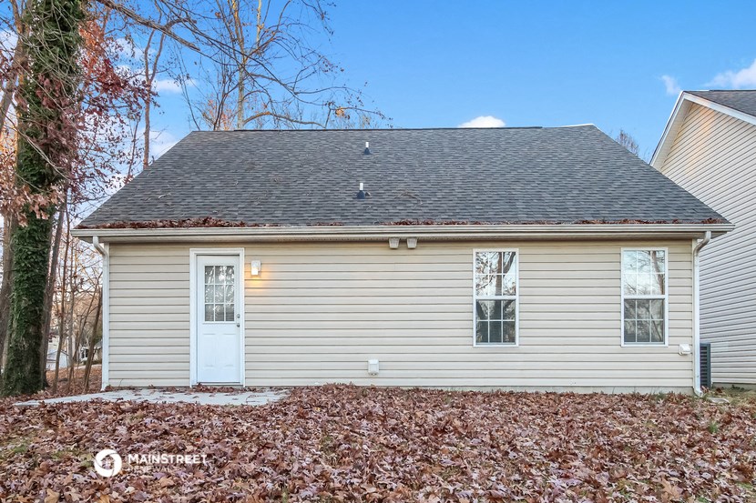 a small house with a white door and a yard with fallen leaves