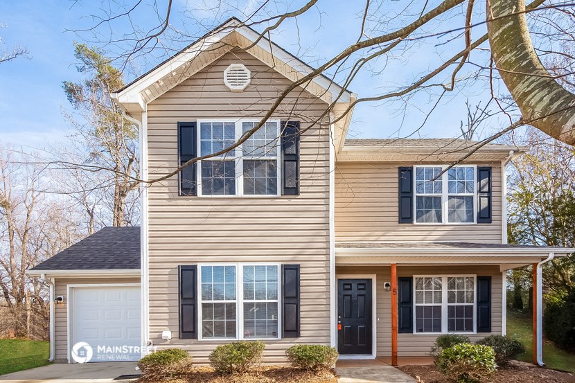 a tan house with black shutters and a white garage door