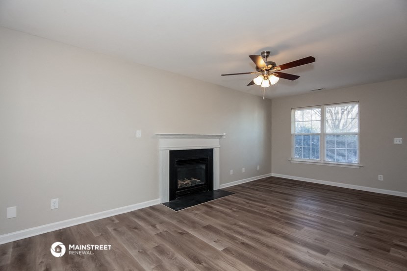 a living room with a fireplace and a ceiling fan