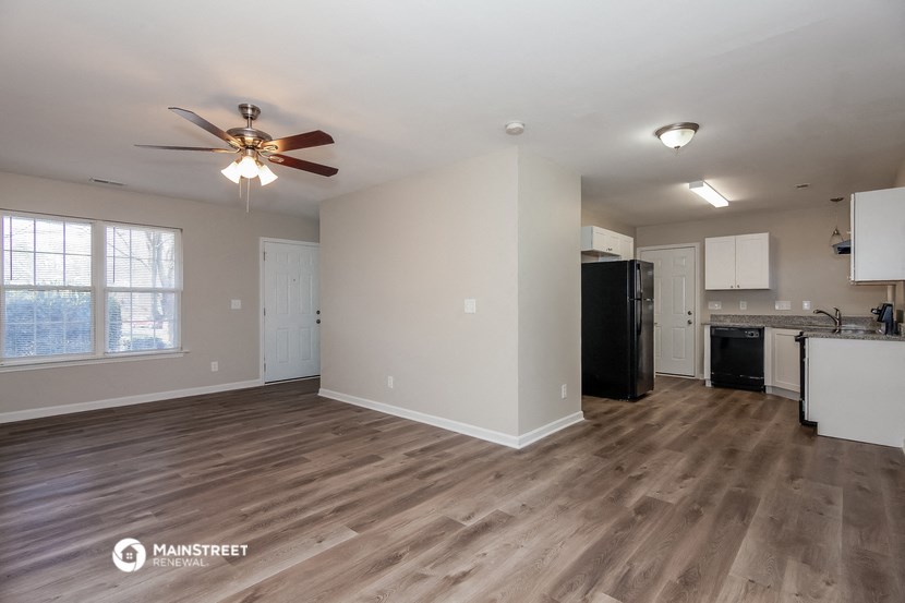 an empty living room and kitchen with a ceiling fan