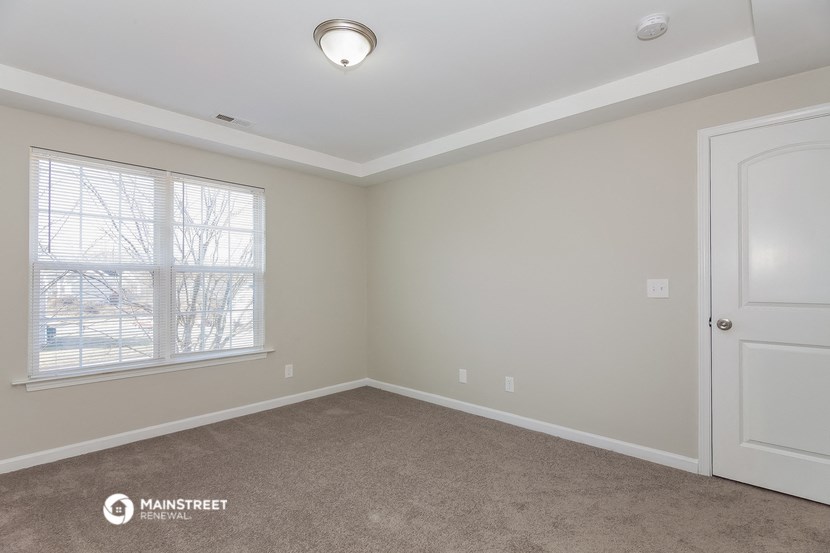an empty room with a window and a white door