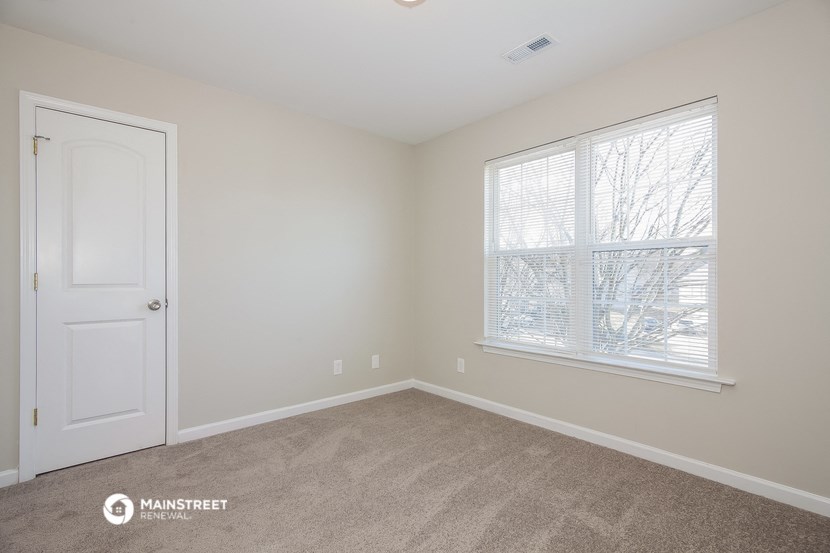 a bedroom with a large window and a white door