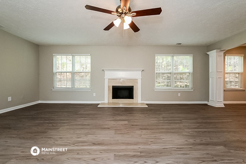 the living room has a fireplace and a ceiling fan