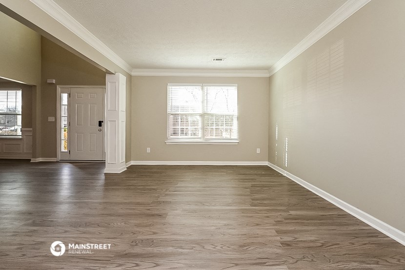 an empty living room with wood floors and a white door