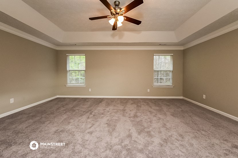 an empty living room with carpet and a ceiling fan