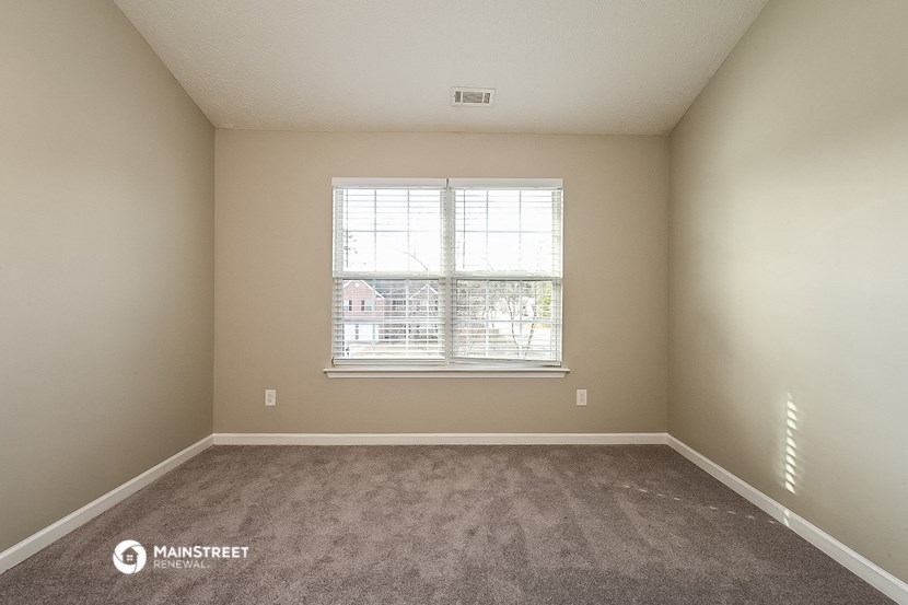an empty room with a window and carpet