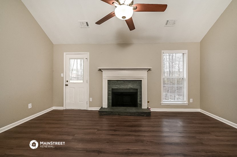 the living room has a fireplace and a ceiling fan